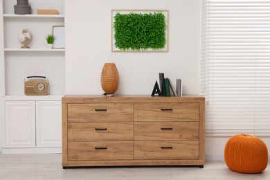 Green artificial plant wall panel and chest of drawers in light room. Interior design