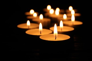 Photo of Burning candles on black background, closeup. Memory day