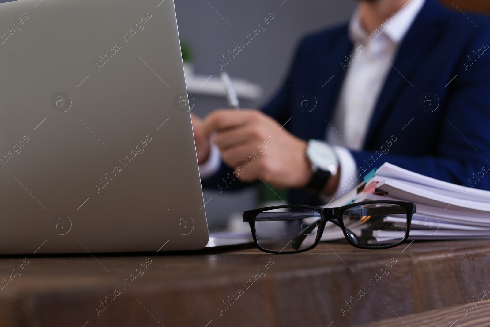 Photo of Glasses, laptop and stack of documents on office table