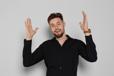 Excited man in black shirt on light grey background