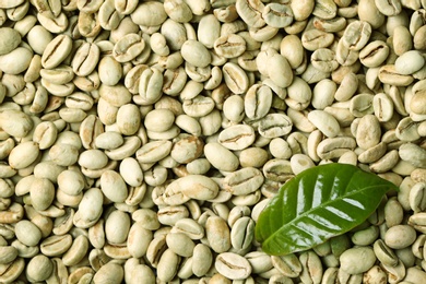 Photo of Green coffee beans and fresh leaf as background, top view