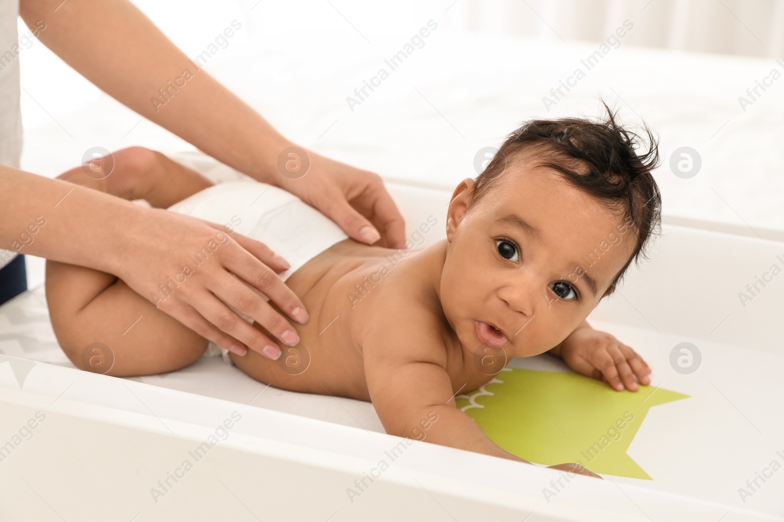 Photo of Mother and her cute child on changing table. Baby massage and exercises