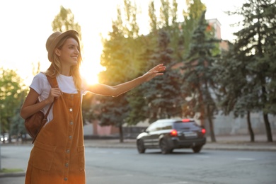 Photo of Young woman catching taxi on city street