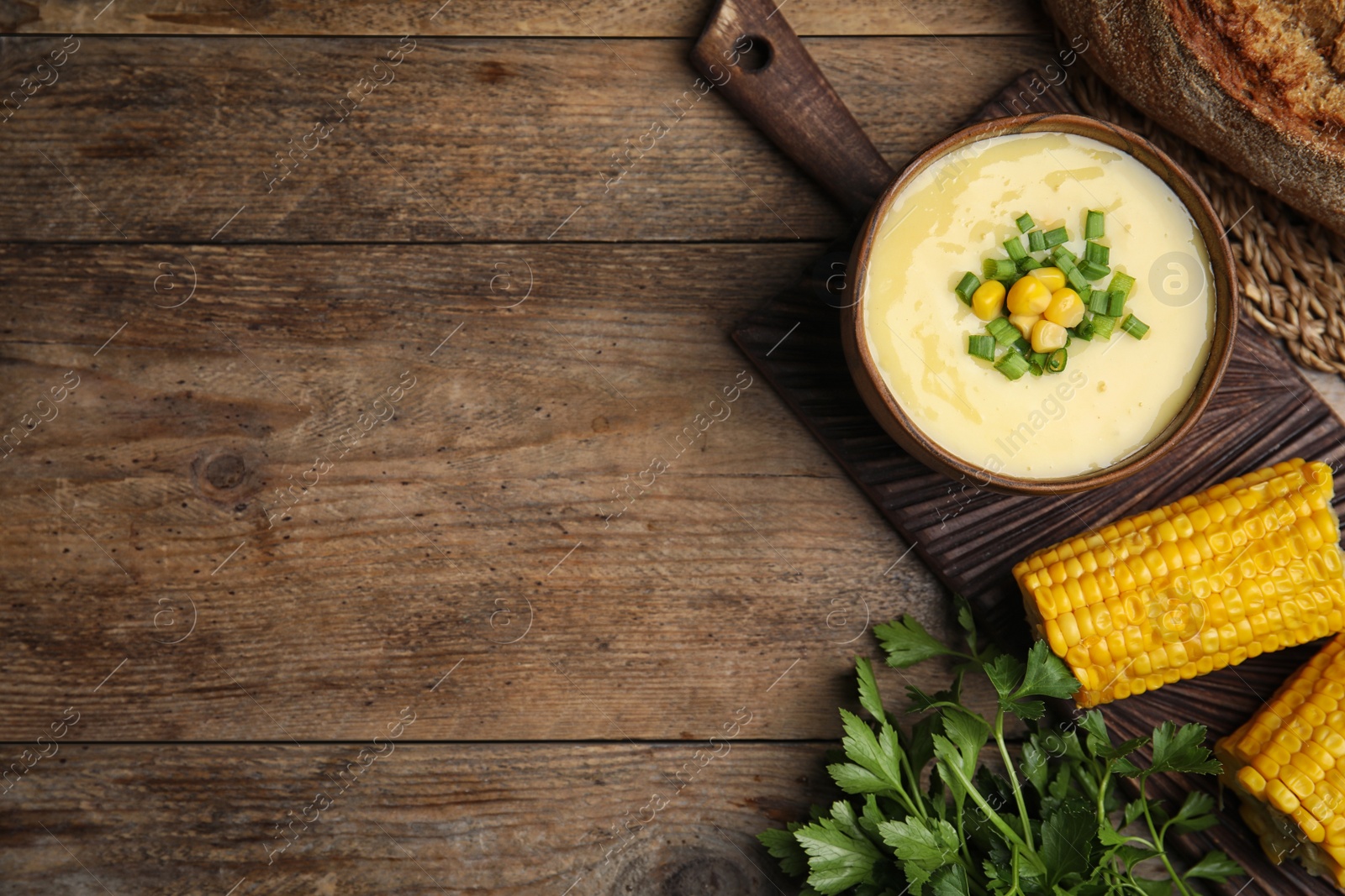 Photo of Delicious corn cream soup served on wooden table, flat lay. Space for text