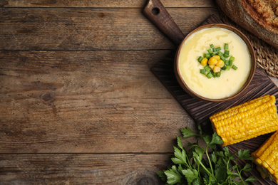 Photo of Delicious corn cream soup served on wooden table, flat lay. Space for text