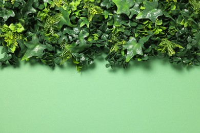 Green artificial plants on color background, top view. Space for text