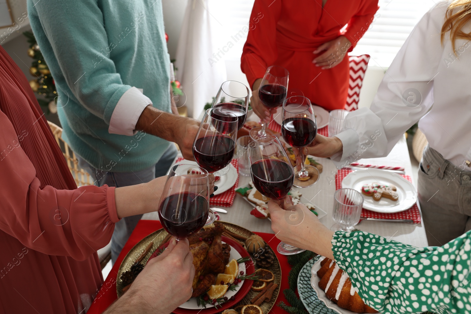 Photo of Family with their friends clinking glasses at festive dinner indoors, closeup. Christmas Eve celebration