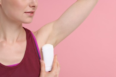 Photo of Woman applying deodorant on pink background, closeup. Space for text