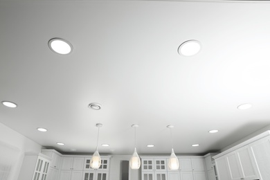 Modern pendant lamps on white ceiling indoors