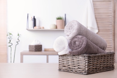 Photo of Basket with rolled fresh towels on table in bathroom. Space for text