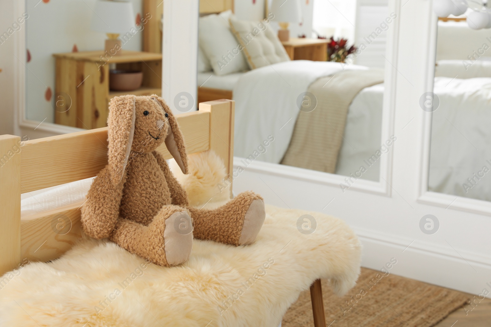 Photo of Toy bunny on faux fur in modern girl's bedroom. Interior design