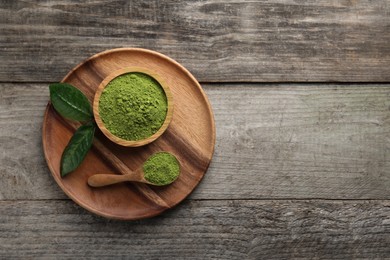 Photo of Green matcha powder and leaves on wooden table, top view. Space for text