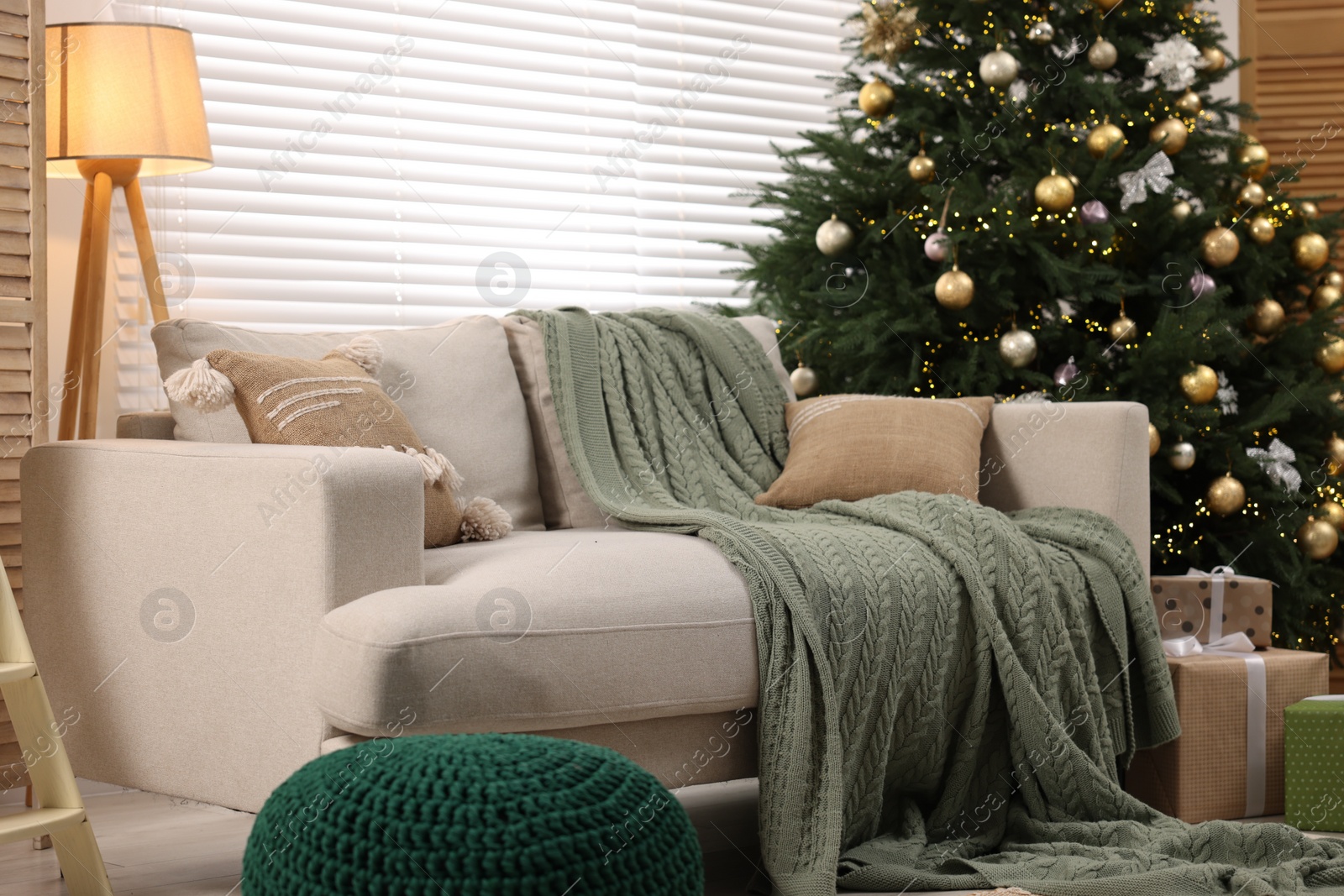 Photo of Sofa near Christmas tree in room. Festive interior design