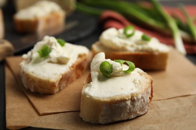 Photo of Bread with cream cheese and green onion on table, closeup