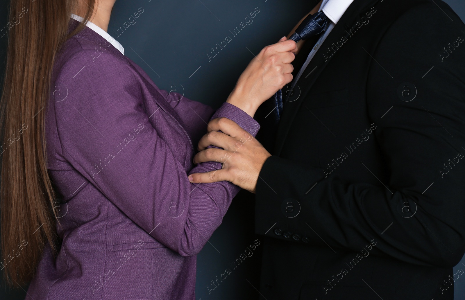 Photo of Woman molesting her male colleague on dark background, closeup. Sexual harassment at work