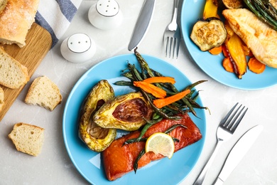 Photo of Delicious cooked salmon and vegetables served on grey table, flat lay. Healthy meals from air fryer