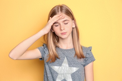 Teenage girl suffering from headache on color background