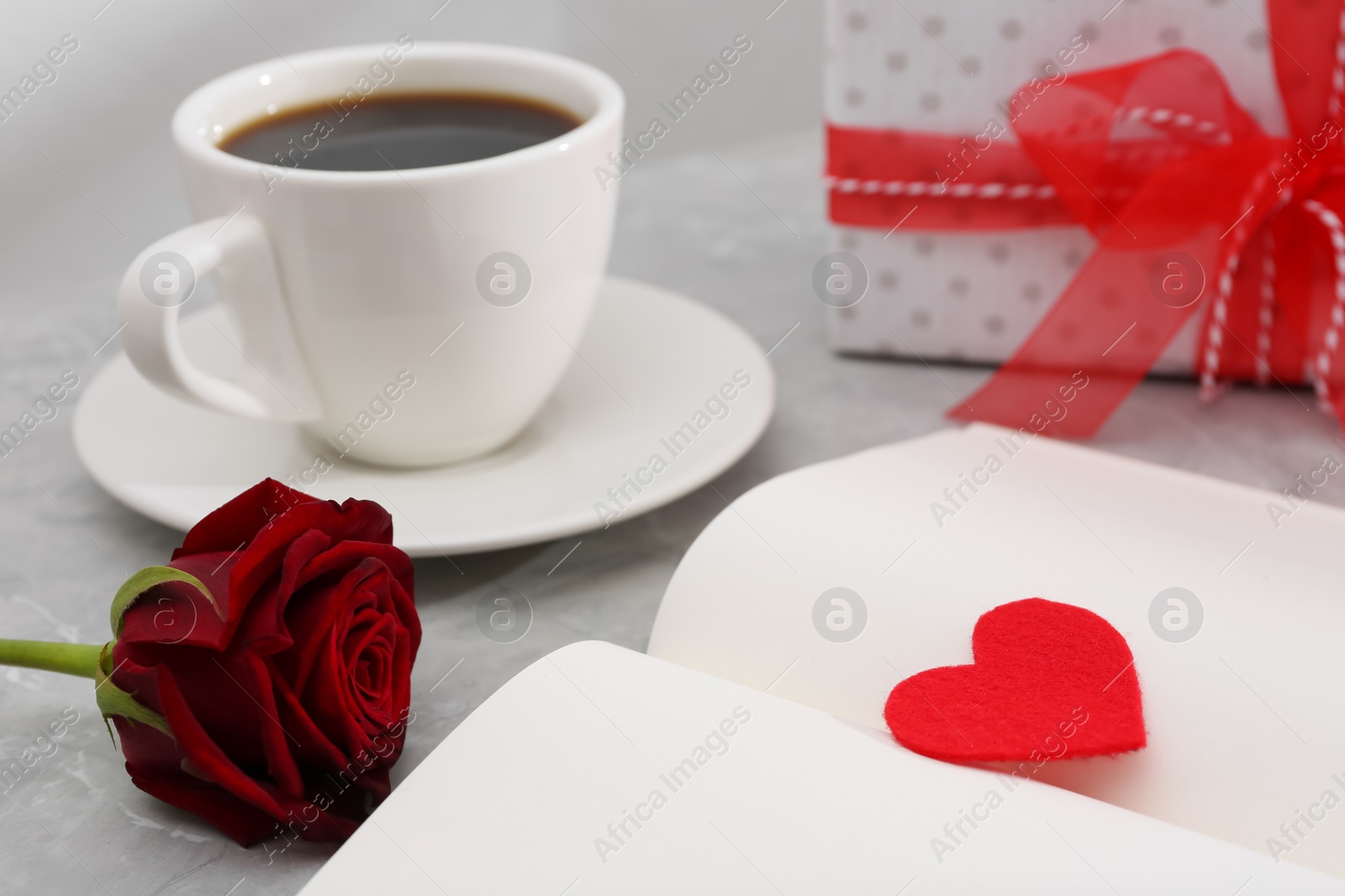 Photo of Open notebook with red heart, coffee and rose flower on light grey table. Valentine's day celebration
