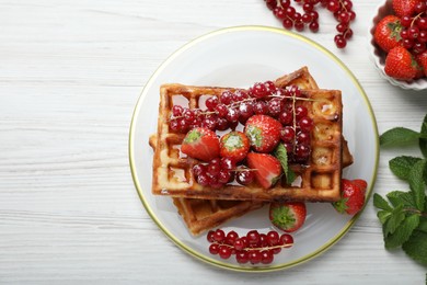 Photo of Plate of delicious Belgian waffles with berries and honey on white wooden table, flat lay. Space for text