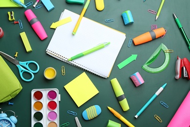 Photo of Different bright school stationery on green background, flat lay