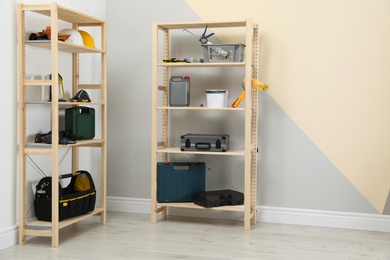 Photo of Wooden shelving units with different instruments near color wall, space for text. Stylish room interior