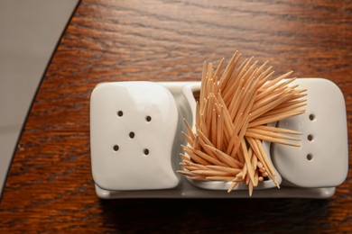 Holder with salt, pepper and toothpicks on wooden table, top view