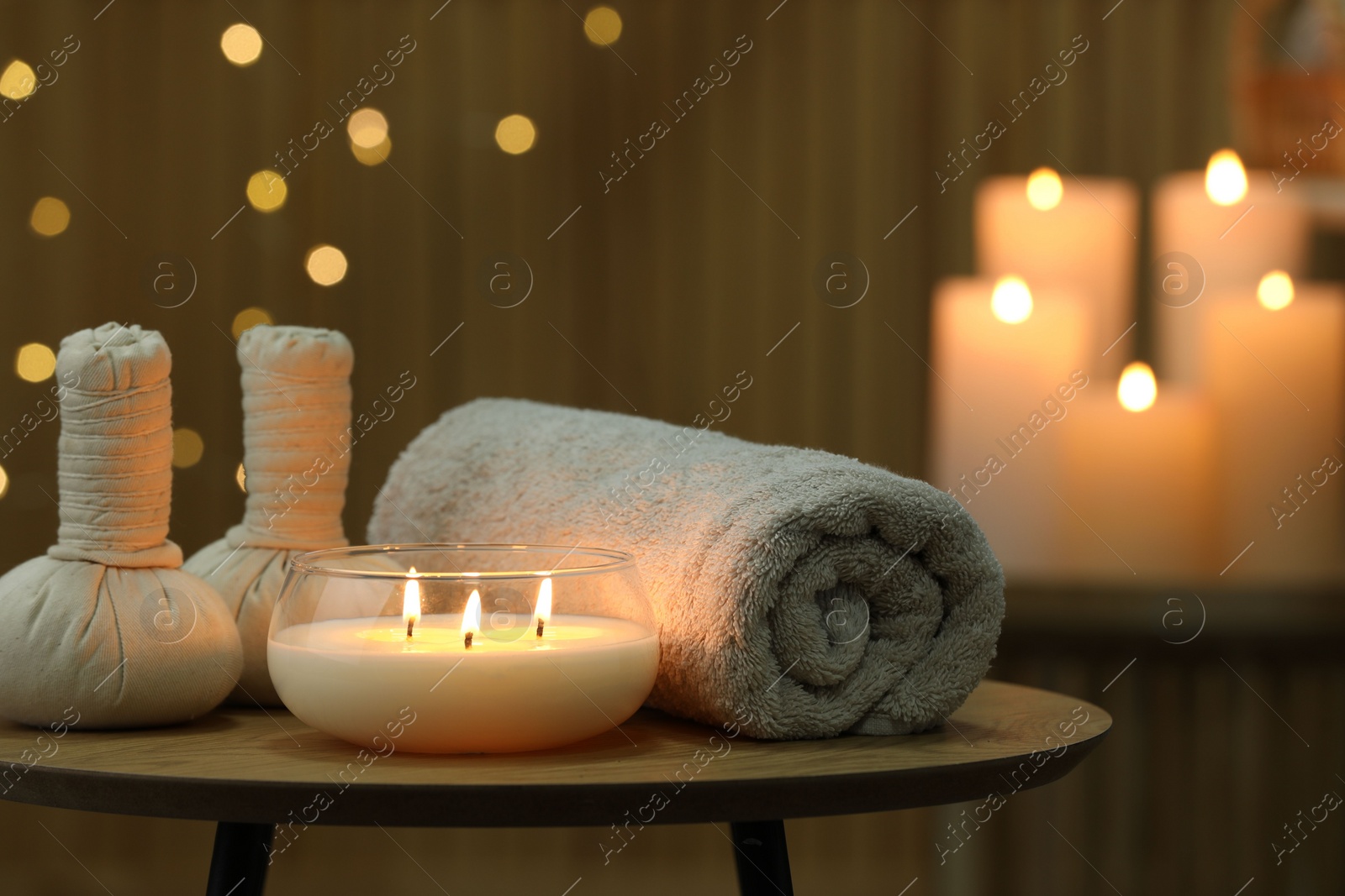 Photo of Spa composition. Herbal bags, towel and burning candle on wooden table