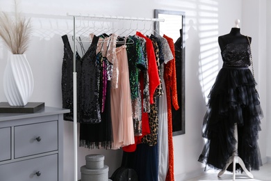 Photo of Rack with collection of beautiful festive clothes in stylish room interior