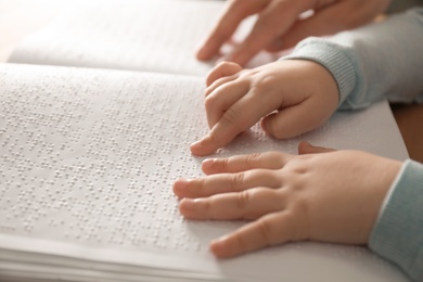 Photo of Blind child reading book written in Braille, closeup