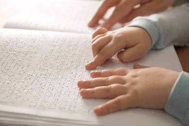 Blind child reading book written in Braille, closeup