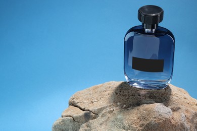 Photo of Stylish presentation of luxury men`s perfume on stone against light blue background. Space for text