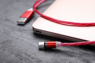 Photo of USB cable with type C connector and laptop on grey table, closeup