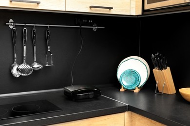 Sandwich toaster and kitchen utensils on black countertop