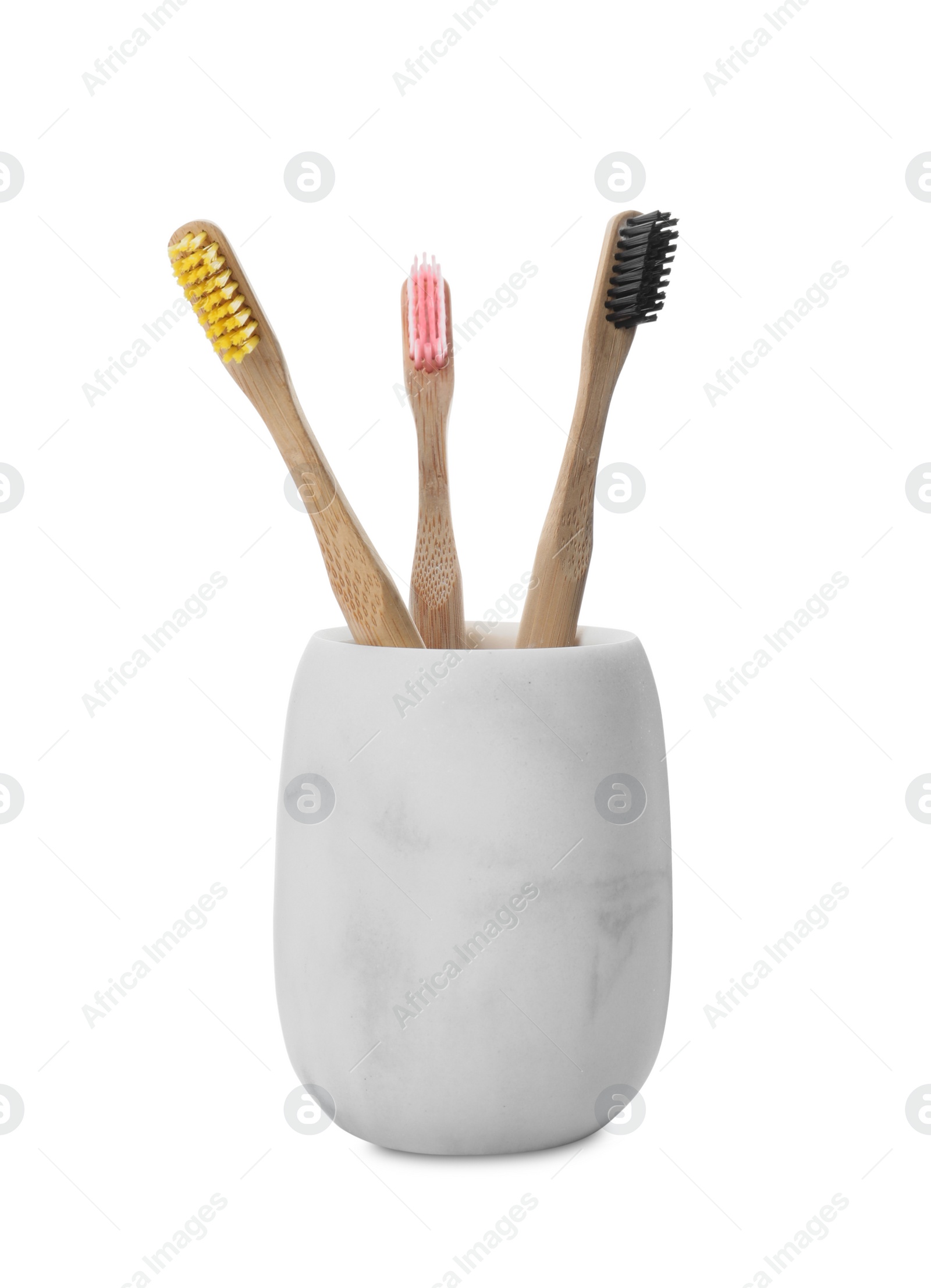 Photo of Bamboo toothbrushes in ceramic holder on white background