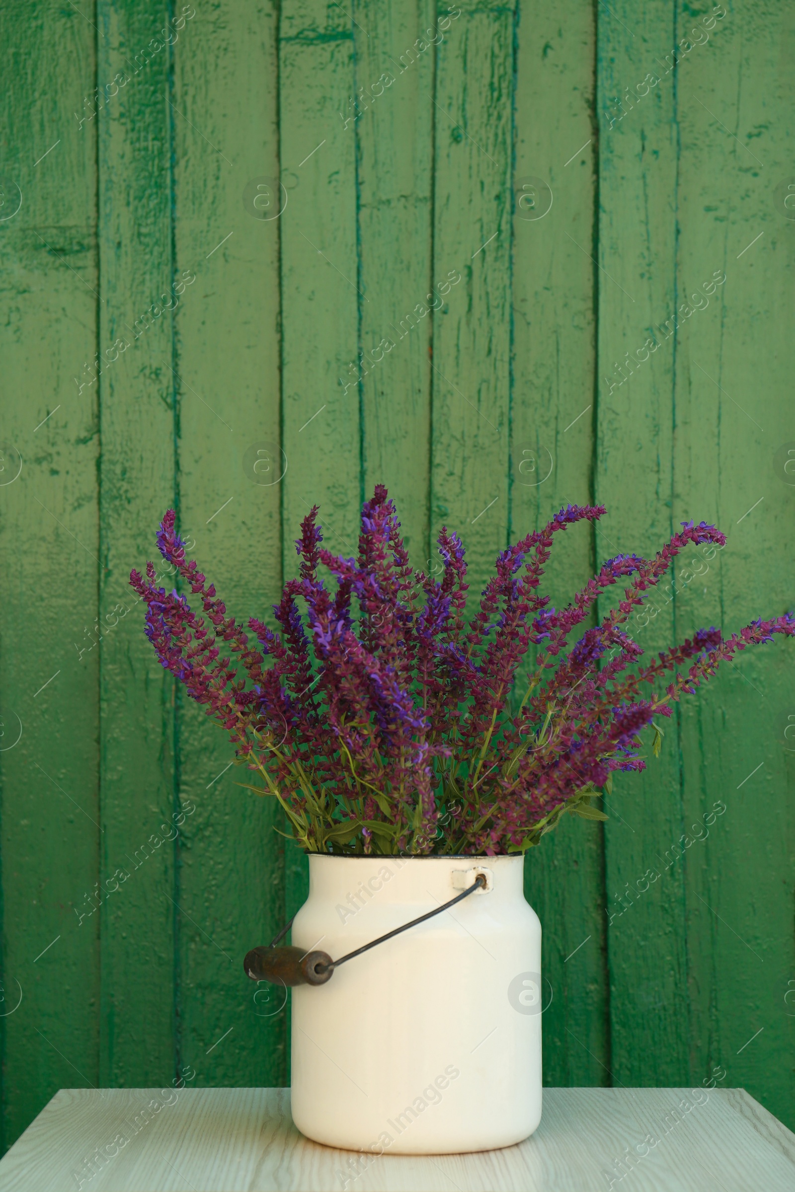 Photo of Beautiful bouquet with field flowers in can on white wooden table