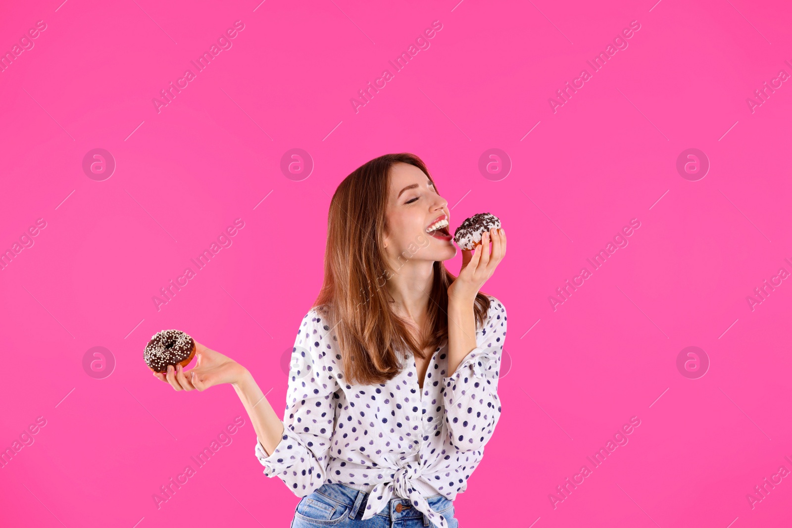 Photo of Beautiful young woman with donuts on light pink background