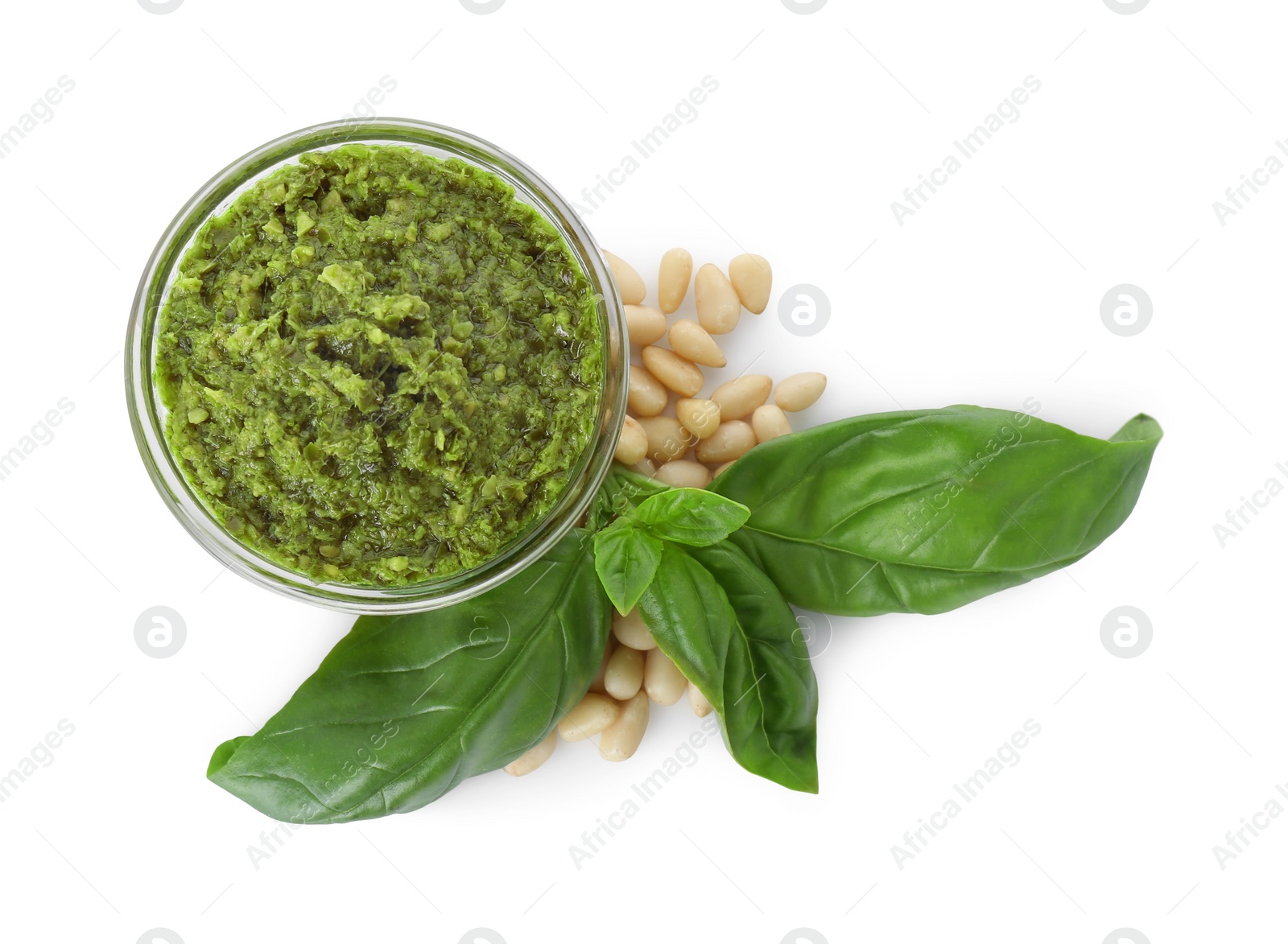 Photo of Delicious pesto sauce in bowl, pine nuts and basil leaves isolated on white, top view