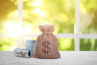 Image of Burlap bag with dollar sign and banknotes on white table indoors