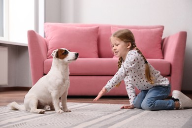 Cute little girl playing with her dog at home. Childhood pet