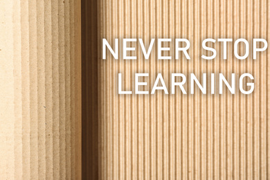 Image of Phrase NEVER STOP LEARNING on corrugated cardboard, top view