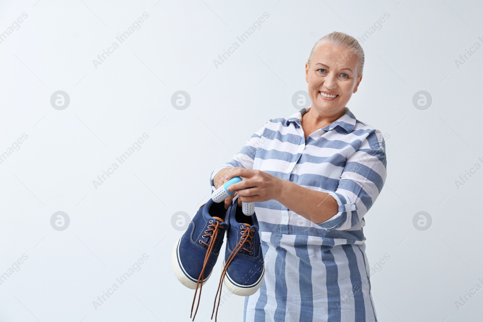 Photo of Woman putting capsule shoe freshener in footwear on white background. Space for text