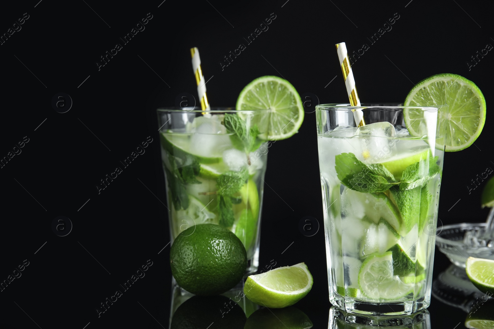 Photo of Delicious mojito and ingredients on black background. Space for text