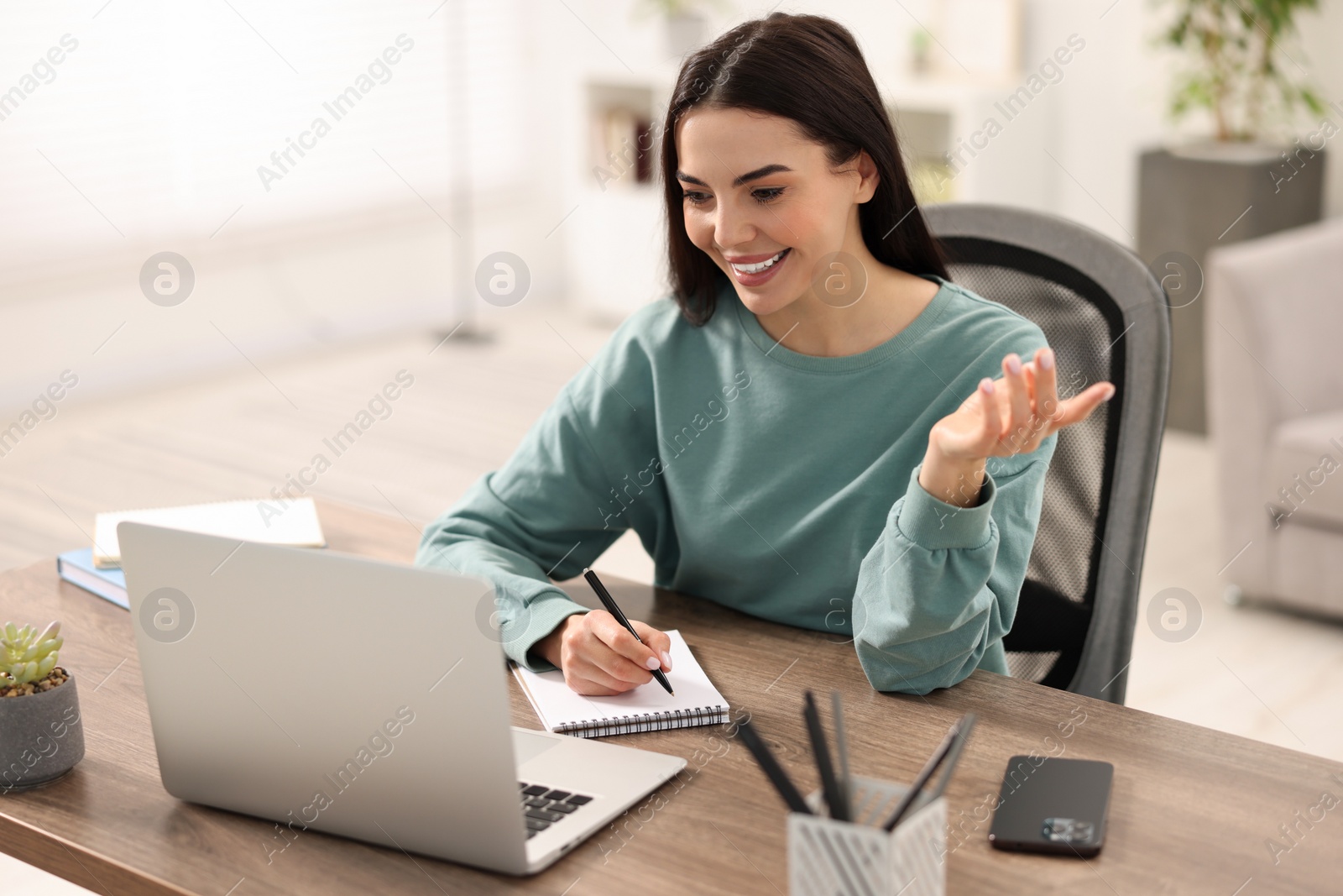 Photo of Young woman using video chat during webinar at table in room