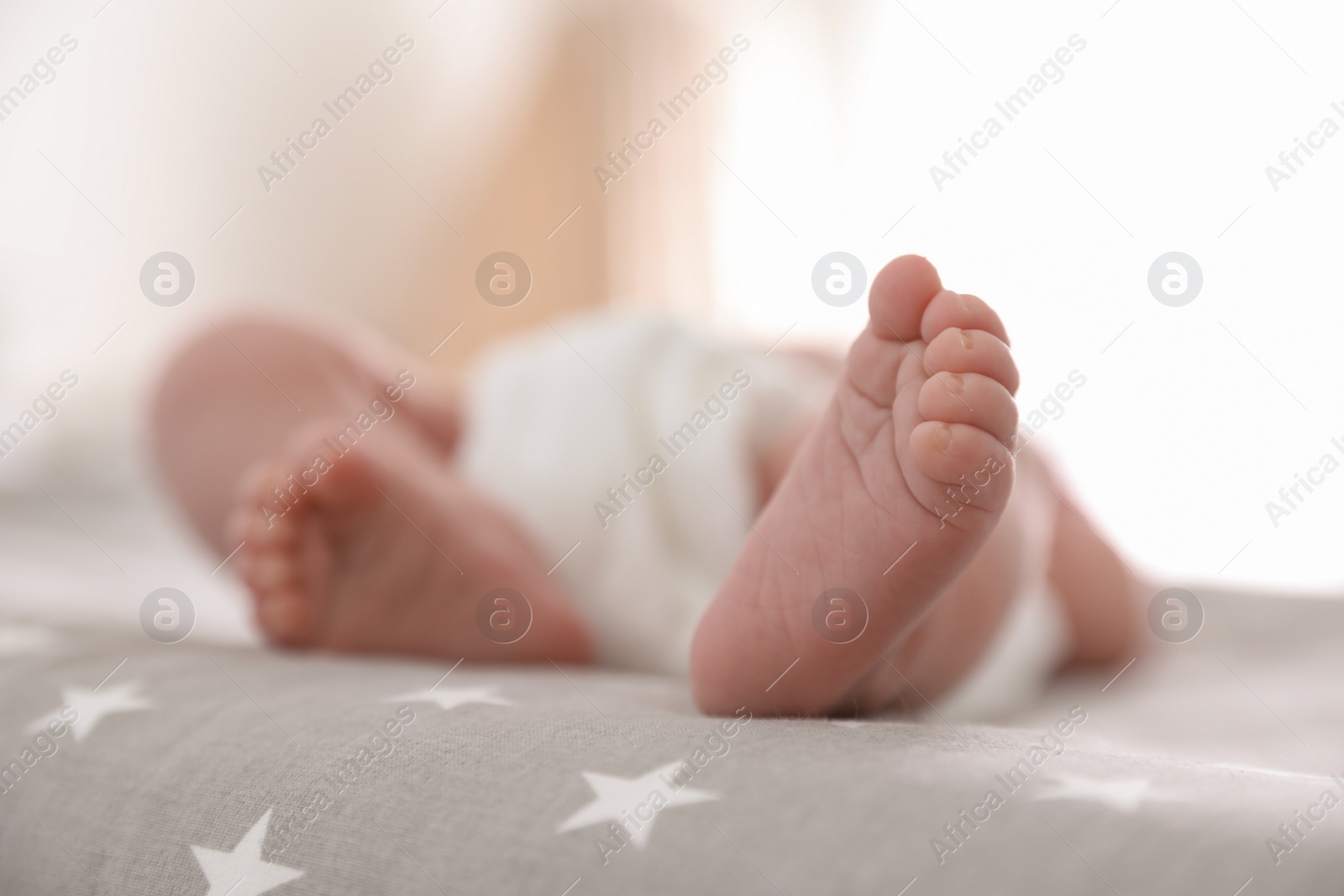 Photo of Cute little baby lying on bed at home, closeup of legs