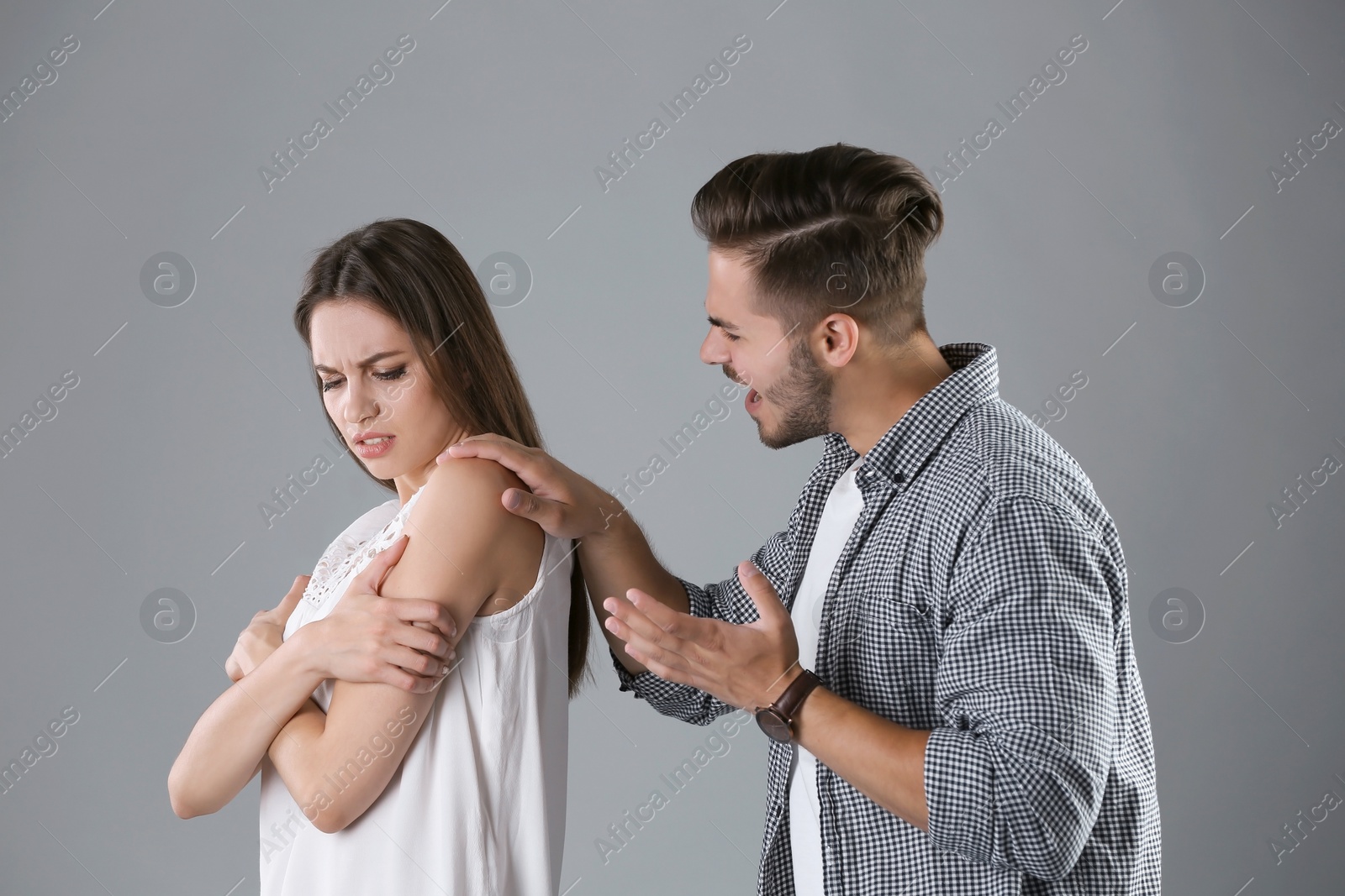 Photo of Young couple having argument on grey background. Relationship problems
