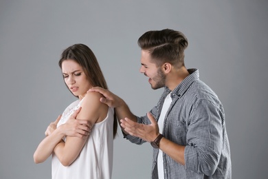 Young couple having argument on grey background. Relationship problems