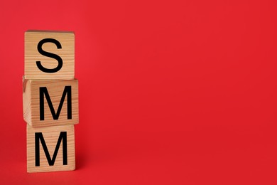 Photo of Wooden cubes with abbreviation SMM (Social media marketing) on red background. Space for text