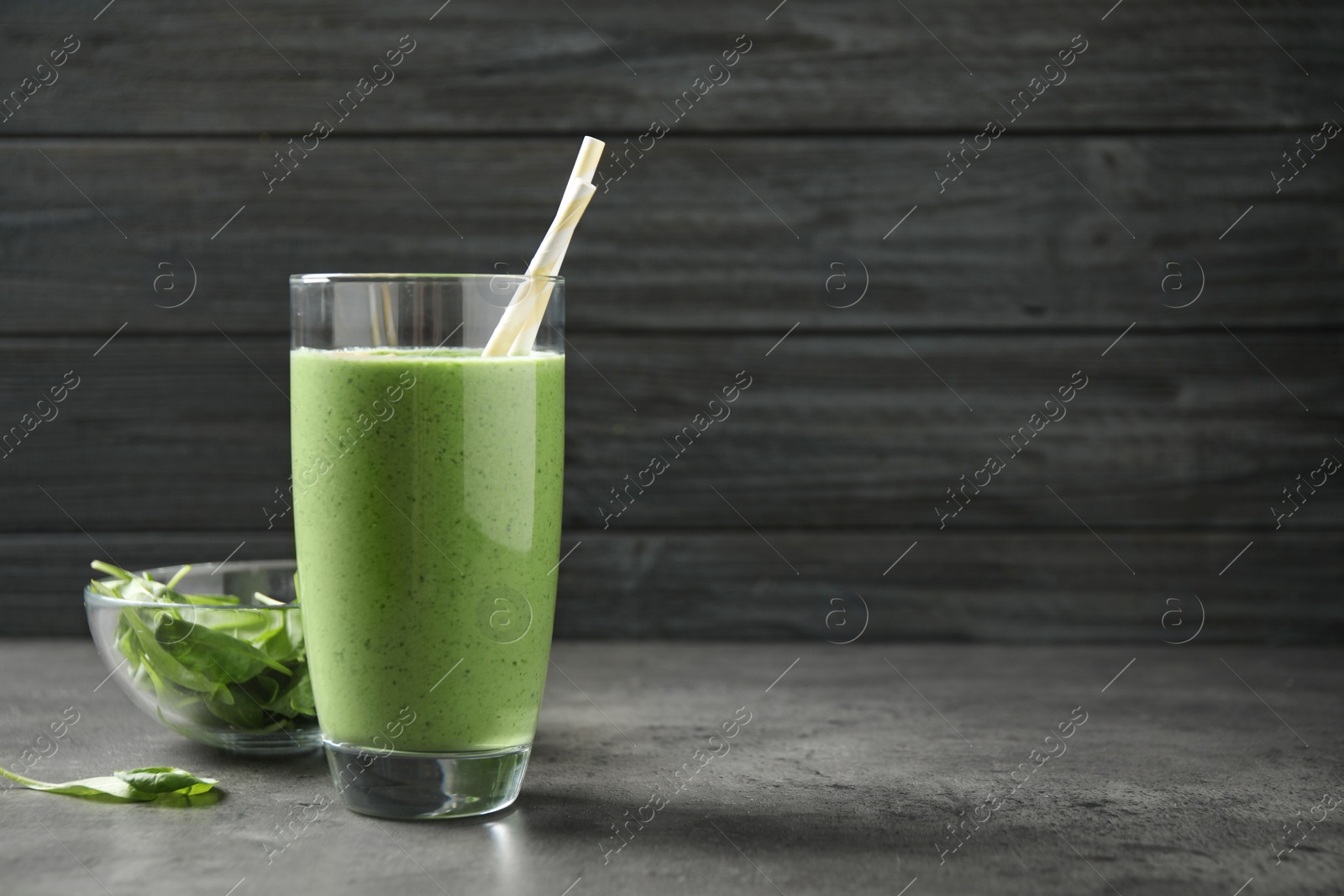 Photo of Glass of healthy green smoothie with fresh spinach on grey table. Space for text