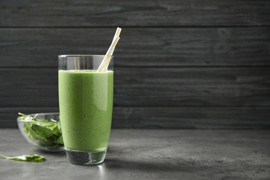 Photo of Glass of healthy green smoothie with fresh spinach on grey table. Space for text