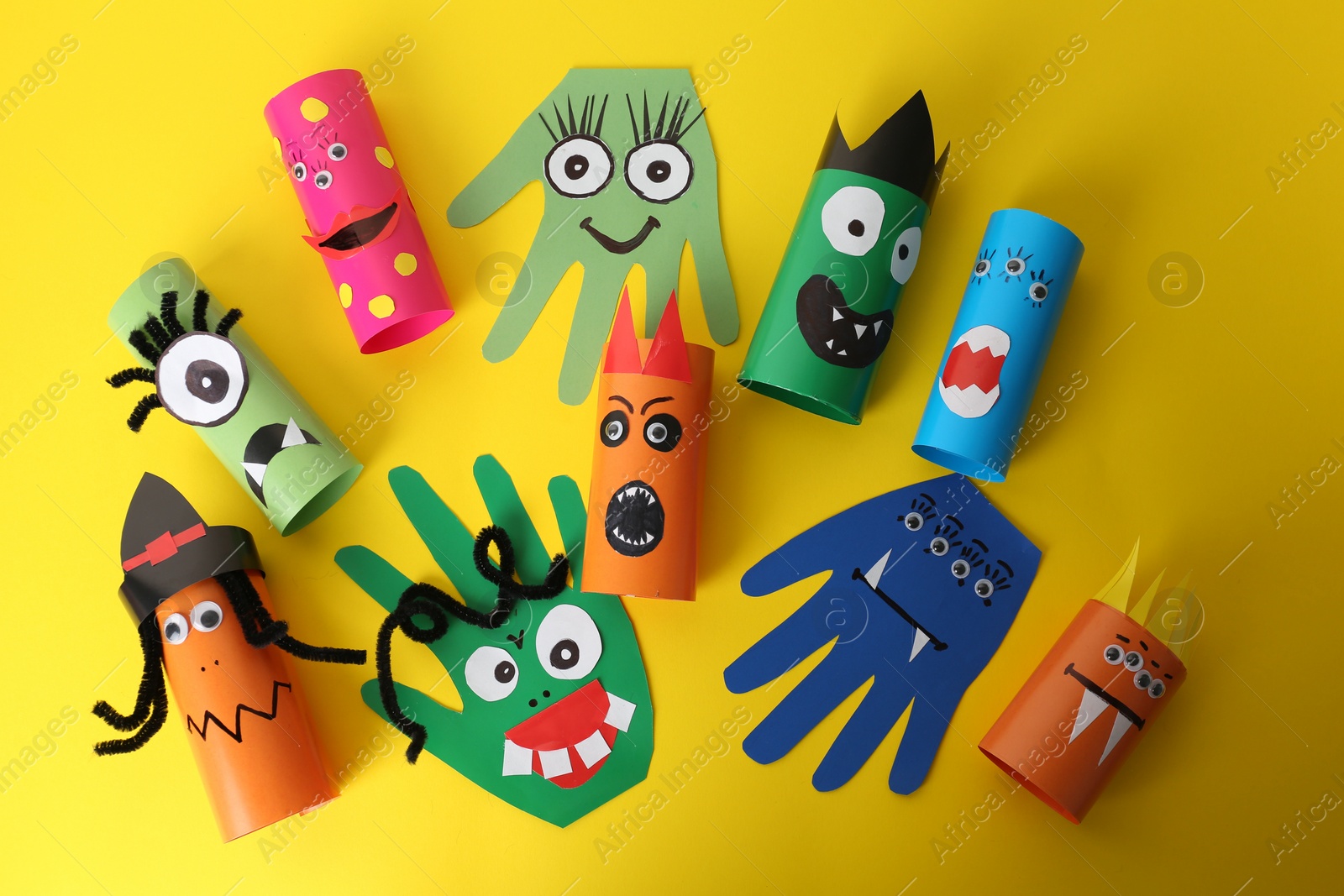 Photo of Funny monsters on yellow background, flat lay. Halloween decoration